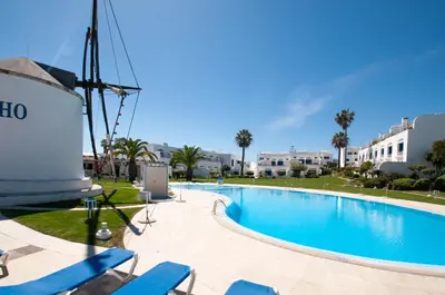 a swimming pool with blue chairs next to a building at Windmill by OCvillas in Albufeira