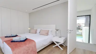 a white bedroom with a bed and a chair at OneSixOne-Cleverdetails, Luxury villa, Sleeps 8 adults 2 children, Private pool and Jacuzzi in Vilamoura