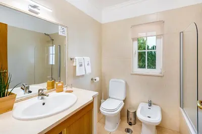 a bathroom with a sink and a toilet and a mirror at Falésia Ocean Villa by The Portuguese Butler in Albufeira