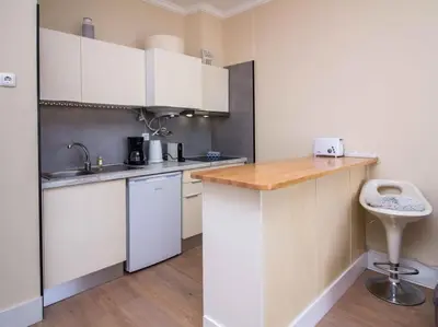 a kitchen with white cabinets and a wooden counter top at Sea View Studio by Stay ici Algarve Holiday Rental in Albufeira
