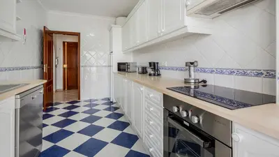 a kitchen with white cabinets and a blue and white checkered floor at Albufeira 3BR with Pool and AC by the beach by LovelyStay in Albufeira