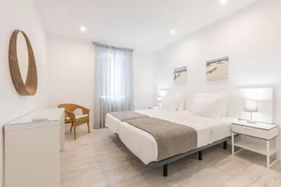 a white bedroom with a bed and a mirror at Apartamentos Baltum in Albufeira