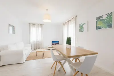 a white living room with a wooden table and chairs at Apartamentos Baltum in Albufeira