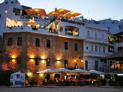 a building with tables and umbrellas in front of it at V4, Villa Jardins Branqueira7 near Beach, Albufeira in Albufeira