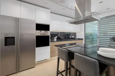 a kitchen with a stainless steel refrigerator and a table at Casa ALBUFEIRA SUNSET in Albufeira