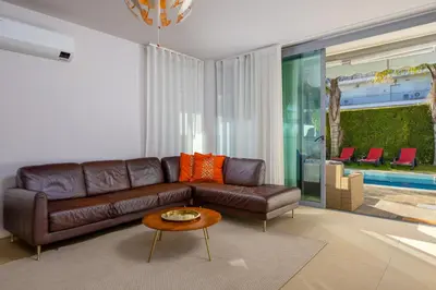 a living room with a brown leather couch and a table at Casa ALBUFEIRA SUNSET in Albufeira
