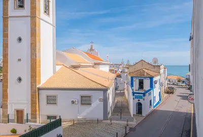 a building with a clock tower next to a street at Beach Studio in Albufeira's old town in Albufeira