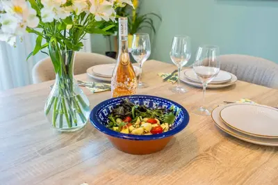 a table with a bowl of salad and a vase of flowers at Luxury Villa in Serene Location with Pool & Private Garden in Quarteira