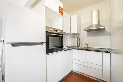 a kitchen with white cabinets and a refrigerator at BeGuest Albufeira Visconde Apartment in Albufeira