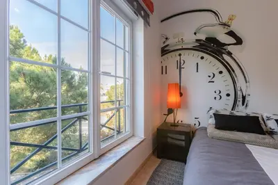 a large clock in a bedroom with a bed and a window at ROJA PÉ - Elegante apartamento T2 com AC perto do Pine Cliffs in Albufeira