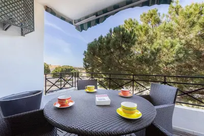 a table with two cups and saucers on a balcony at ROJA PÉ - Elegante apartamento T2 com AC perto do Pine Cliffs in Albufeira