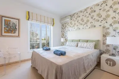 a bedroom with a bed with two blue pillows on it at ROJA PÉ - Elegante apartamento T2 com AC perto do Pine Cliffs in Albufeira
