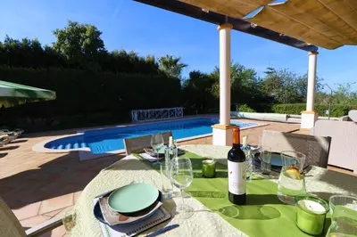 a table with a wine bottle and glasses on a patio at Villa Jóia - 3 Bedroom Villa with Swimming pool in Boliqueime, near Vilamoura, Algarve in Boliqueime