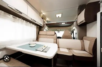 an rv with a white table and chairs and a table at Portugals Infinity - AutoCaravana Luxo in Faro