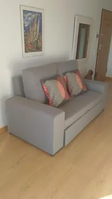 a gray couch with two pillows in a living room at Sunset House Algarve in Faro