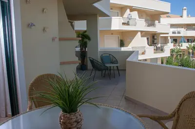 a balcony with a table and chairs and a building at Vila Rosal Margarida Apartment in Albufeira