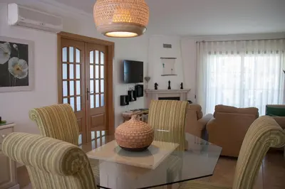 a living room with a glass table and chairs at Vila Rosal Margarida Apartment in Albufeira