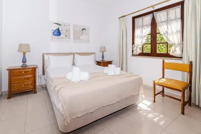 a bedroom with a bed and a chair and a window at Villa Fineli in Vilamoura
