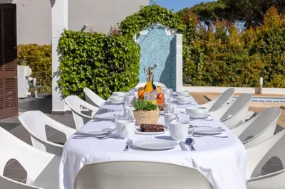 a long table with white chairs and a white table cloth at Villa Fineli in Vilamoura