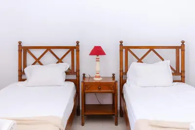 two beds in a room with a lamp on a night stand at Villa Fineli in Vilamoura