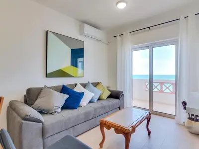 a living room with a couch and a view of the ocean at AL - Apartamento Girassol Beach Front Quarteira in Quarteira