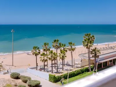 a view of a beach with palm trees and the ocean at AL - Apartamento Girassol Beach Front Quarteira in Quarteira