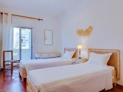 two beds in a room with white walls at AL - Apartamento Maré Alta in Quarteira