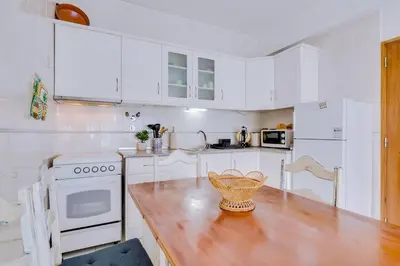 a kitchen with white cabinets and a wooden counter top at Nascente Sea View @Homesbyfc in Quarteira