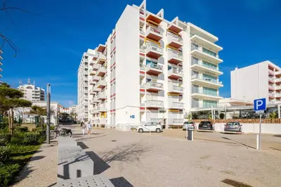 a large white building with cars parked in front of it at Nascente Sea View @Homesbyfc in Quarteira