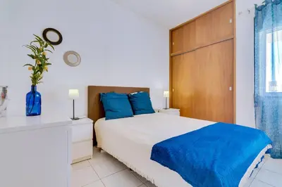 a bedroom with a large bed with blue pillows at Nascente Sea View @Homesbyfc in Quarteira
