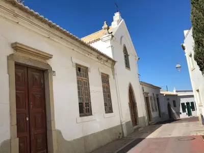 a white building with a brown door on a street at Apartamento Flor de Amendoeira in Albufeira