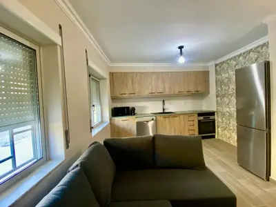 a living room with a couch and a kitchen at Apartamento Flor de Amendoeira in Albufeira
