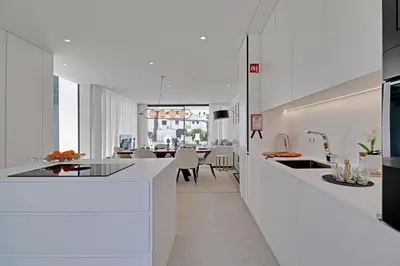a kitchen and dining room with white cabinets and a table at One Six Villa in Vilamoura