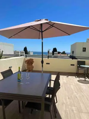 a table with an umbrella on top of a roof at Casa Linda in Albufeira