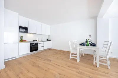 a kitchen with white cabinets and a table and chairs at Alfamar Inês Apartment in Albufeira