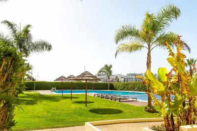 a resort with a swimming pool and palm trees at Marina Vilamoura - Aquamar 005 By Vilamoura Sun in Quarteira