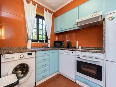 a kitchen with blue cabinets and a washer and dryer at Akivillas Albufeira Felicity in Albufeira