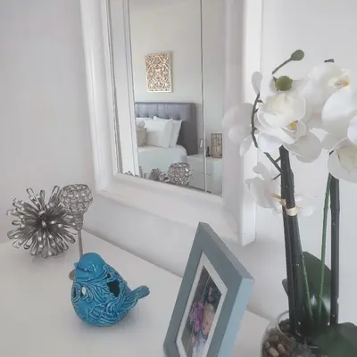 a table with a vase of flowers and a mirror at Ocean Blue II in Quarteira
