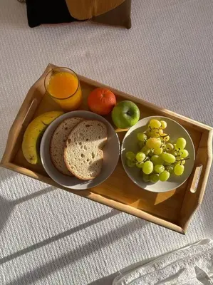 a tray with a plate of fruit and a glass of orange juice at Falésia Beach Apartment in Albufeira