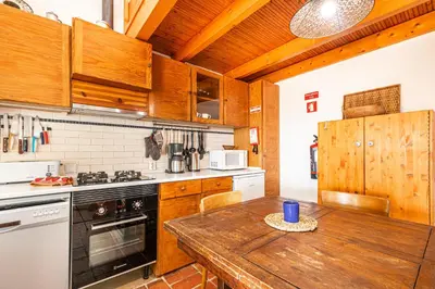 a kitchen with wooden cabinets and a wooden table at BeGuest Casa Romãzeira Typical Vila in Goncinha