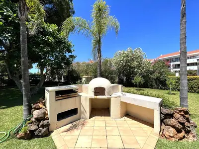 an outdoor oven in a park with palm trees at Vilamoura Amazing Golf Villa With Pool by Homing in Vilamoura