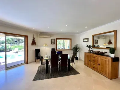 a dining room and living room with a table and chairs at Vilamoura Amazing Golf Villa With Pool by Homing in Vilamoura