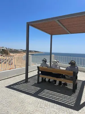 two people sitting on a bench looking at the beach at The Best Downtown Albufeira in Albufeira