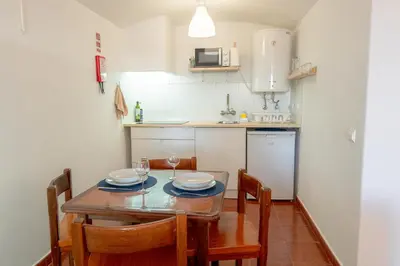 a kitchen with a wooden table with chairs and a dining room at Cozy Albufeira Charm in Albufeira