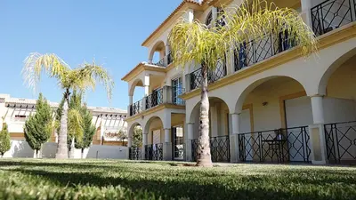 a building with two palm trees in front of it at São Vicente By Albufeira Rental in Albufeira