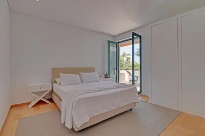 a white bedroom with a bed and a large window at News Apartment in Vilamoura