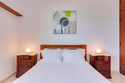 a bedroom with a white bed with two night stands at AL - Apartamento Portas do Mar in Quarteira