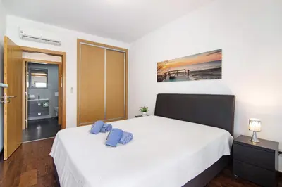 a bedroom with a bed with two blue pillows on it at Apartamento Oceano in Albufeira