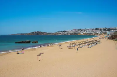 a beach with a bunch of chairs and people on it at Barracuda A14 in Albufeira