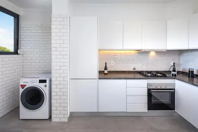 a kitchen with white cabinets and a washer and dryer at Casa Relax à Olhos Albufeira in Albufeira